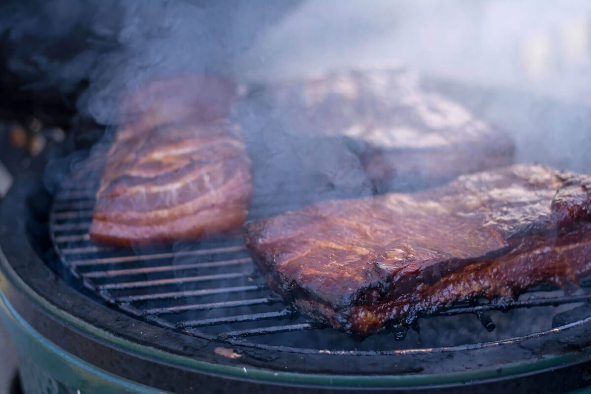 Three slabs of bacon smoking on the Big Green Egg.