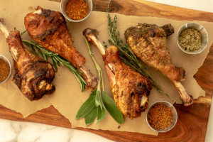 Grilled Turkey Legs on a cutting board with butcher paper and seasoning