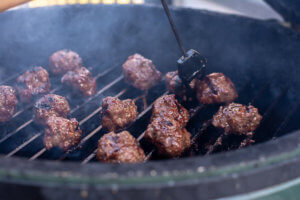 The Big Green Egg Grill with the GrillGrate and Meatballs being brushed with the Asian Chili Sauce