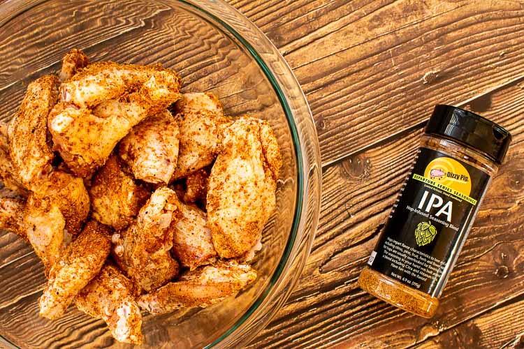 Top Down view of bowl of chicken wings with the bottle of DizzyPig's IPA rub