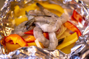 A Double Layer of Foil hold colorful peppers, onions and the peeled shrimp