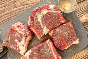 Raw Steak seasoned with garlic salt and pepper on a cutting board