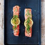 two thin salmon steaks on a pan with lemon and rosemary on top