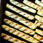 Slices of grilled zucchini in a cast iron skillet and sprinkled with fresh herbs