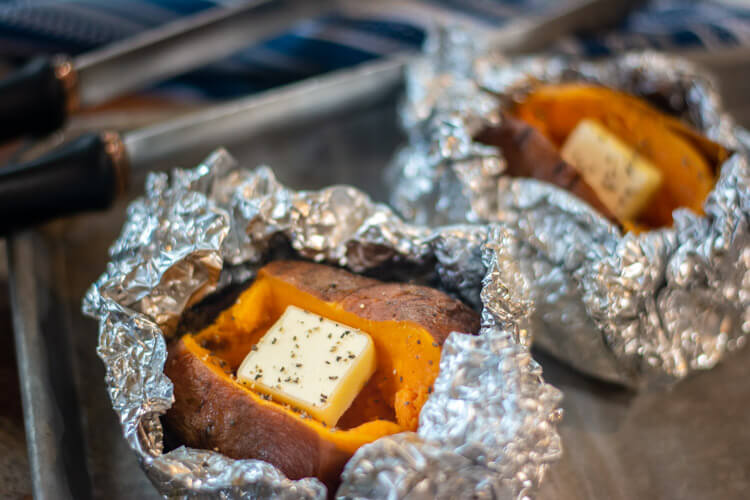 two grilled baked sweet potatoes on a sheet pan read for serving