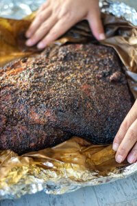 unwrapping the smoked brisket after finishing in the oven