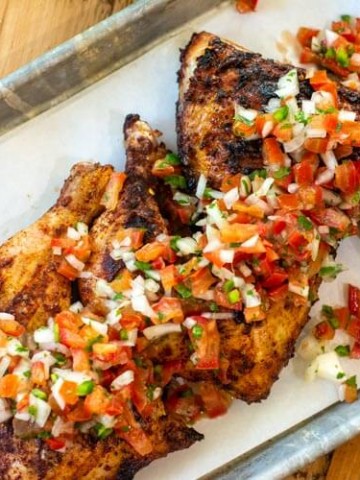 sheet pan with leg quarters and covered in fresh pico