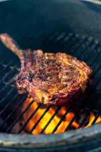 grilled cowboy ribeye receiving its searing over a hot grill