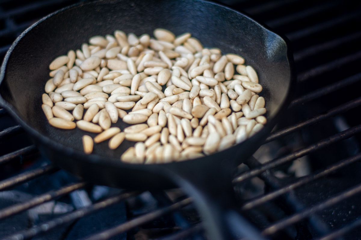 pine nuts in a cast iron skillet on the grill
