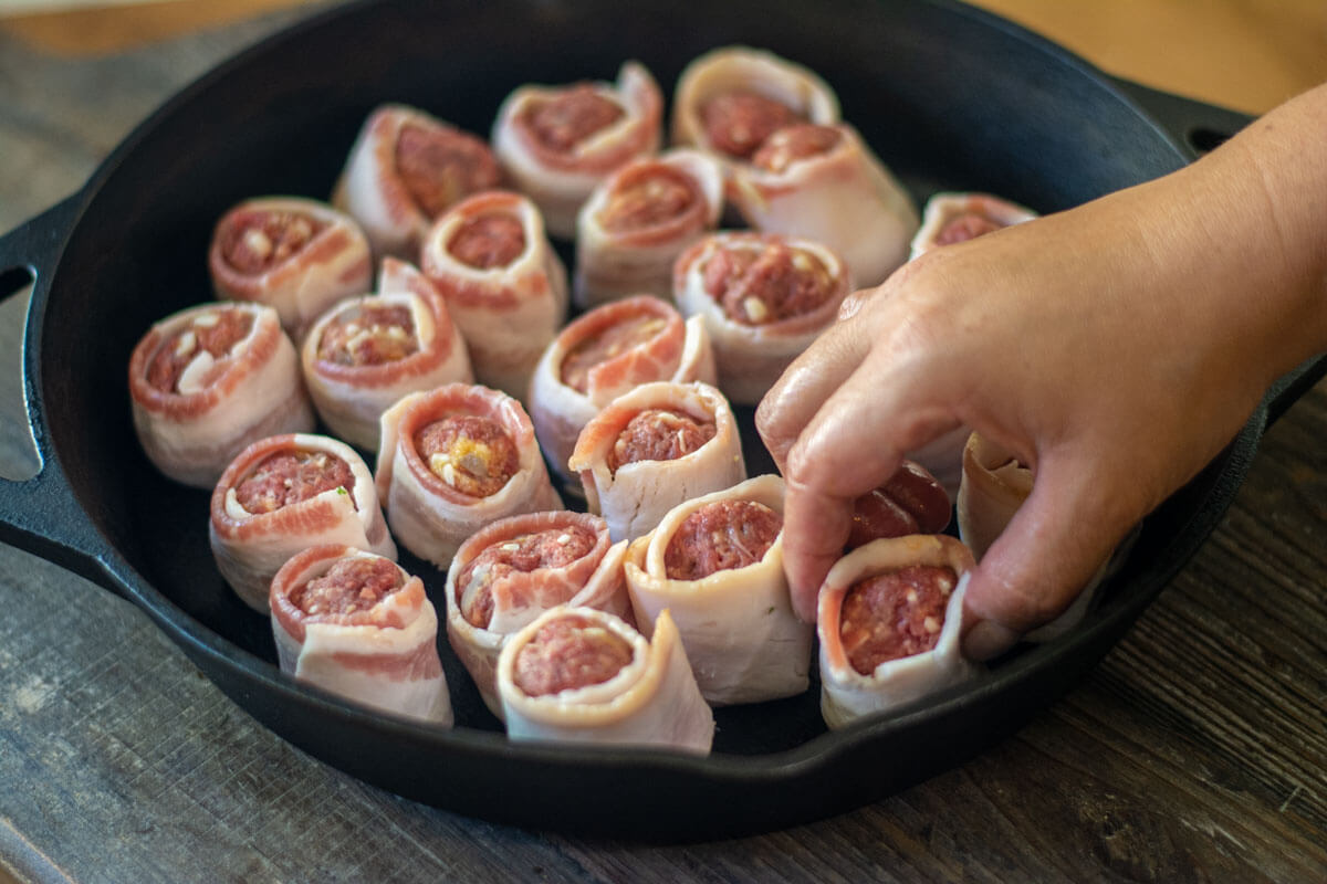 adding bacon wrapped bison meatballs to the cast iron.