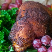 smoked turkey on a platter with parsley, grapes and an other fruit