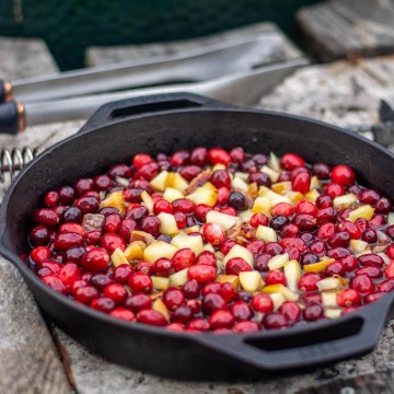 cast iron skilled on the grilling table filled with cranberries and other fruit.