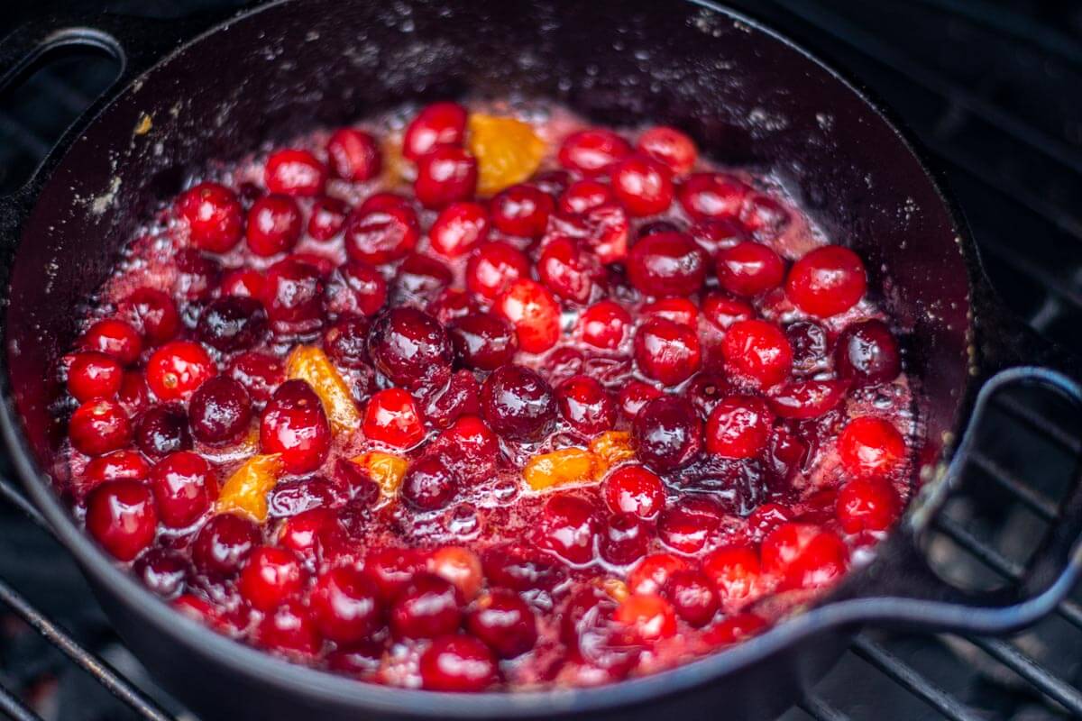 cranberries and clementines breaking down in the cast iron over the open flame of the grill.