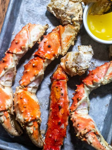 grilled crab legs on a serving tray and ready to be cracked open and dipped in butter.
