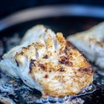 fillet of lingcod on the grill and sizzling in a cast iron griddle.