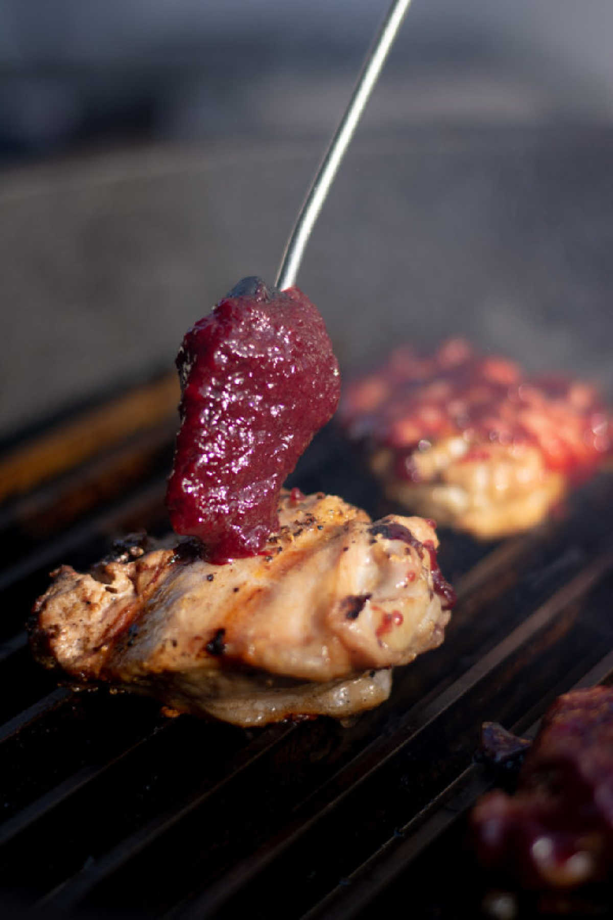brushing on the homemade bourbon and cherry BBQ sauce on the grilled chicken.
