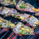 three skewers over the hot coals with the cilantro and lime brushed on.