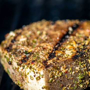 swordfish steak on the grill grate with sear marks and coated in a homemade jerk seasoning rub.