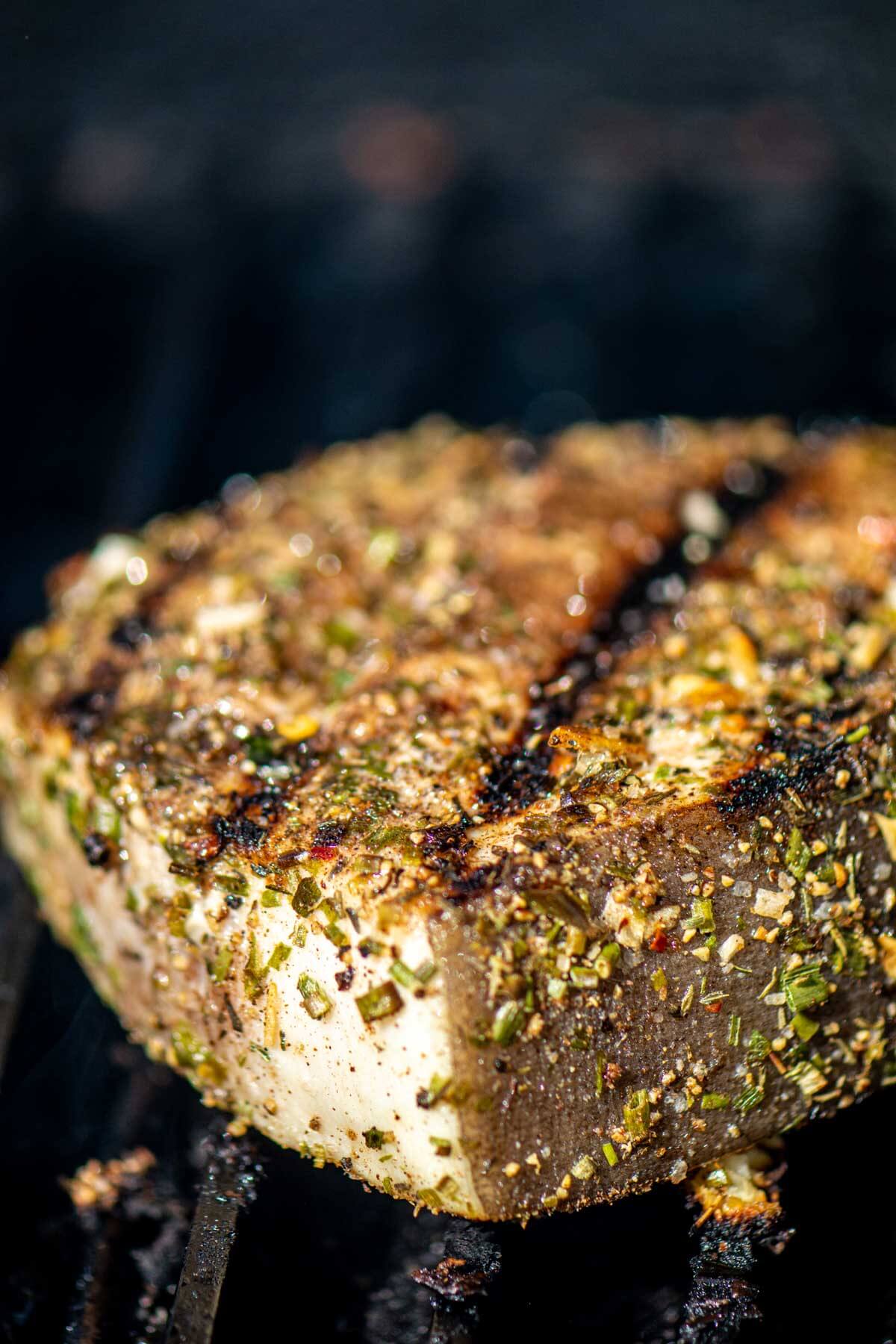 swordfish steak on the grill grate with sear marks and coated in a homemade jerk seasoning rub.