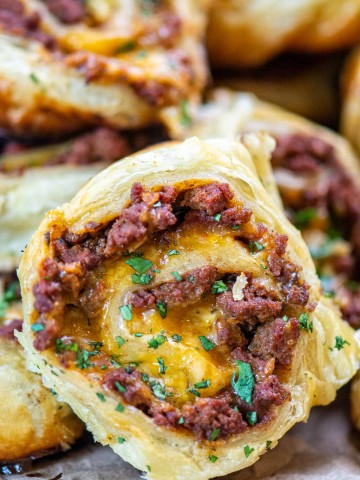 pile of ground elk pinwheels with puff pastry bread and sprinkled with cilantro.