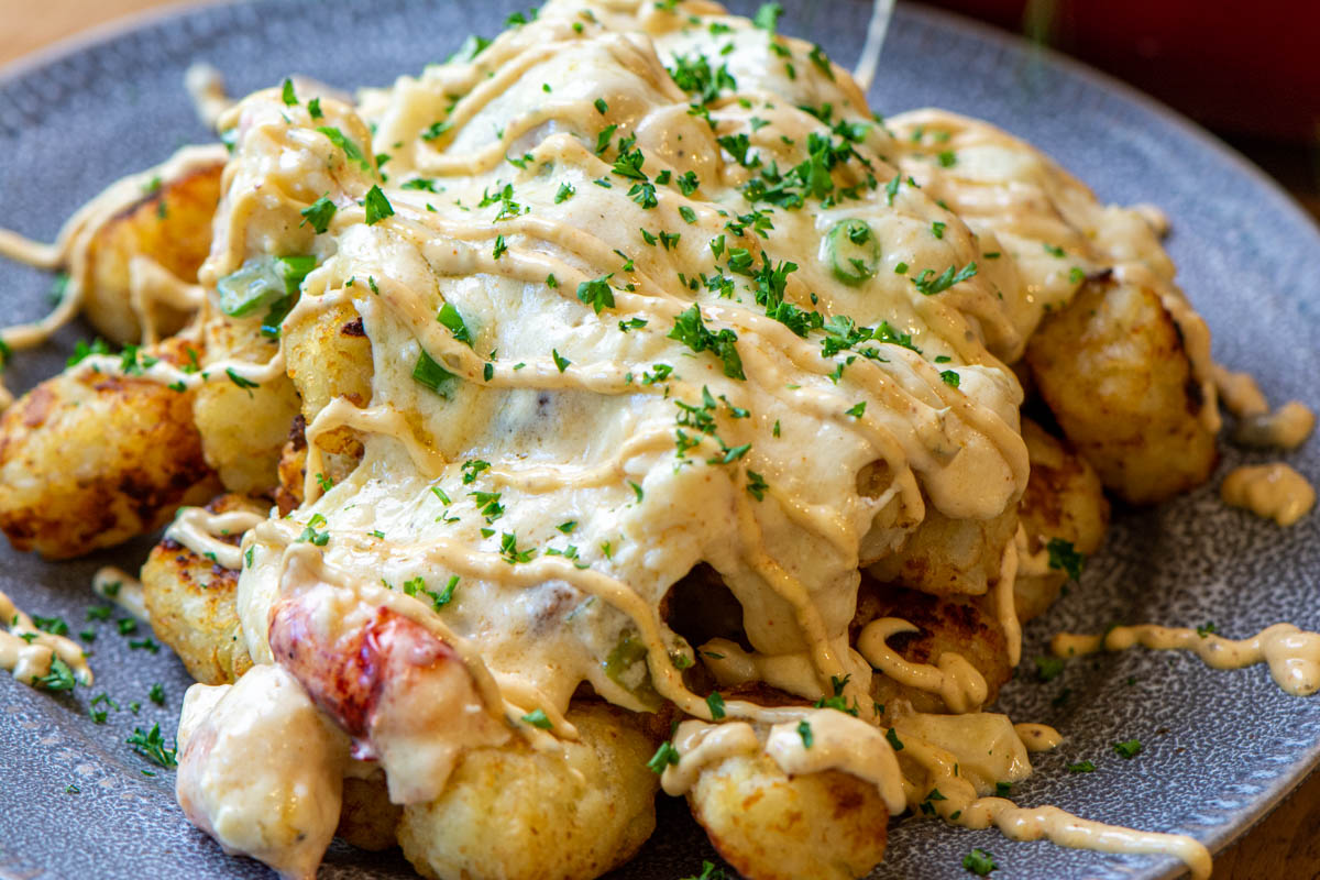 plate of grilled tater tots with a creamy mixed seafood topping.