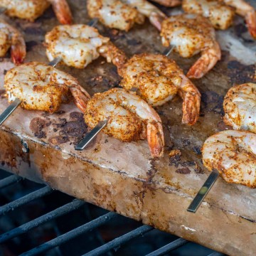 shrimp skewers on a salt block covered in a fajita seasoning.