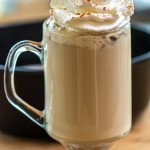 creamy brown pumpkin spiced latte in a glass bug and topped with whipped cream.