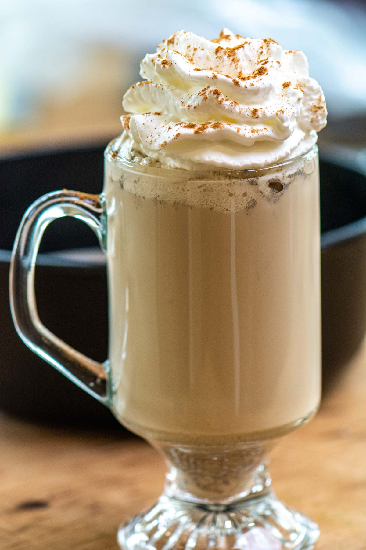 creamy brown pumpkin spiced latte in a glass bug and topped with whipped cream.