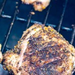 grilled chicken thigh with lemon and pepper seasoning over the grill.