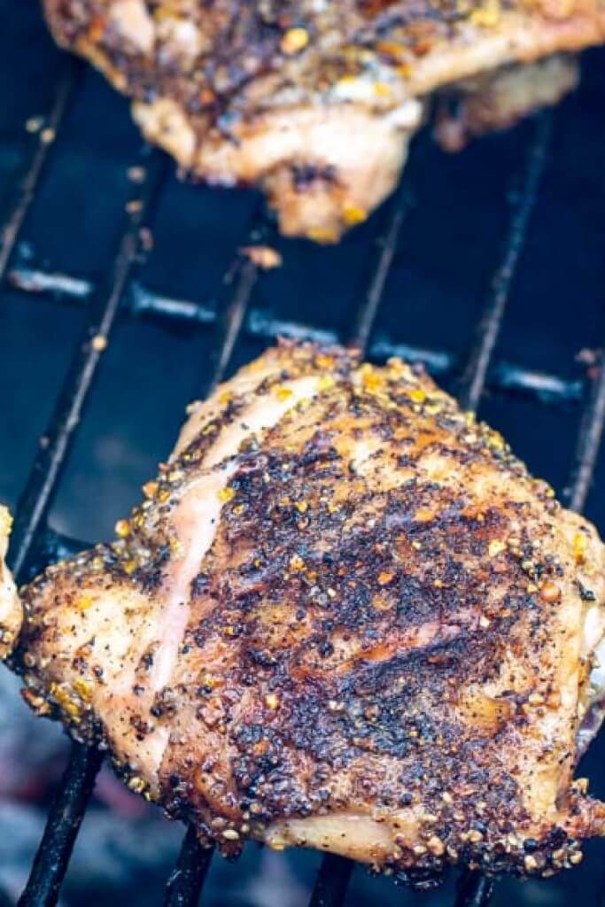 grilled chicken thigh with lemon and pepper seasoning over the grill.