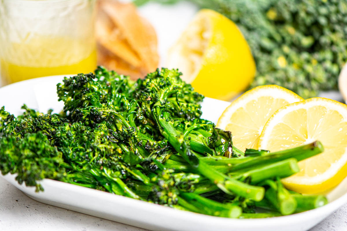 plate of broccolini with lemons, and a jar of the vinaigrette in the background.