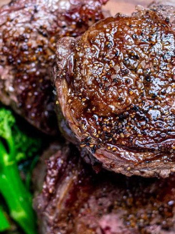 grilled and seared ribeye cap steaks piled on a cutting baord.