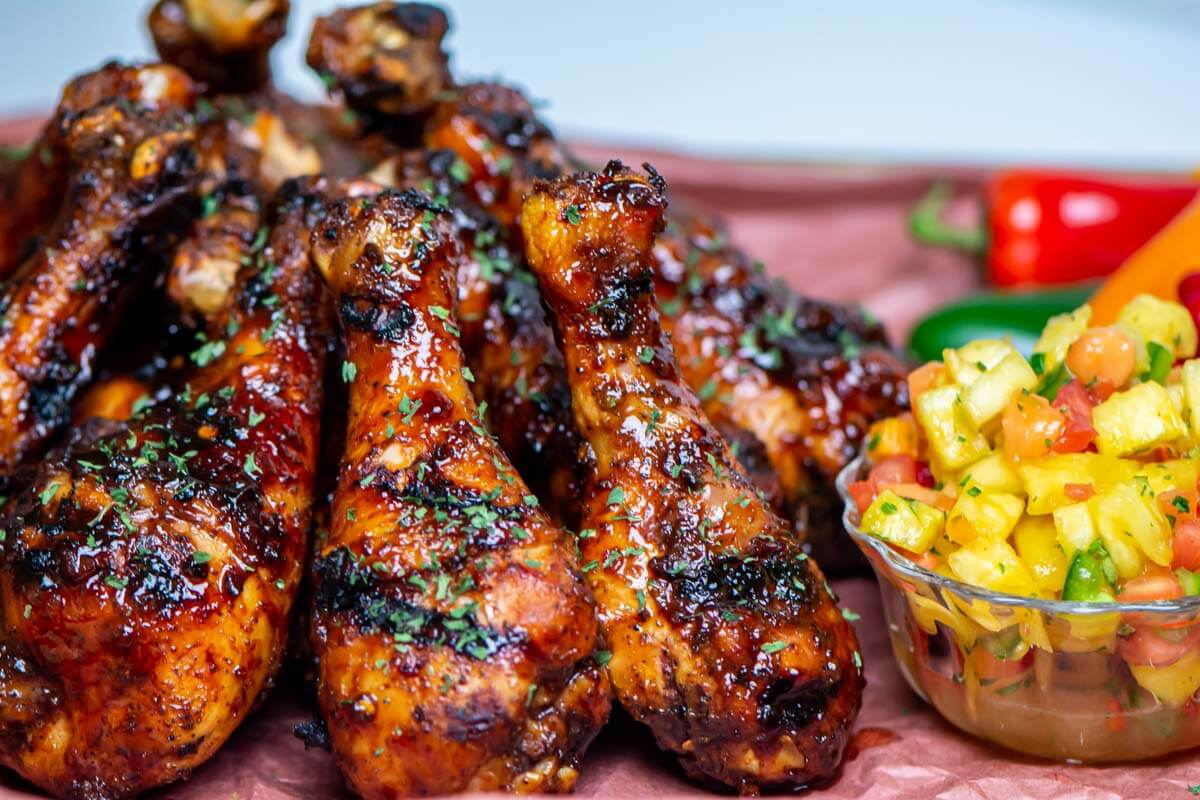 pile of glazed chicken drumsticks with a pineapple salsa.