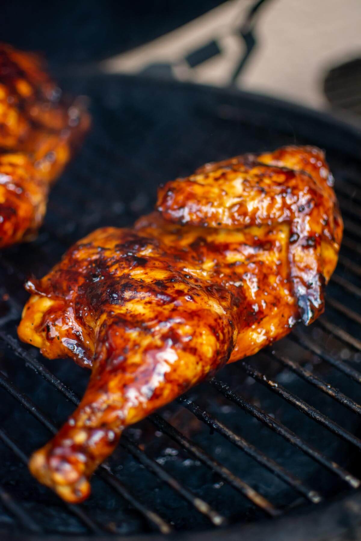 grilled half chicken on the grill covered in a sweet and tangy teriyaki BBQ sauce.