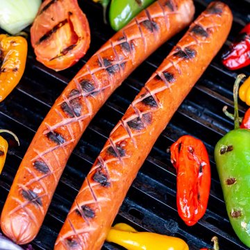 Grilled kielbasa with the score marks opened and seared with fresh peppers and onions.