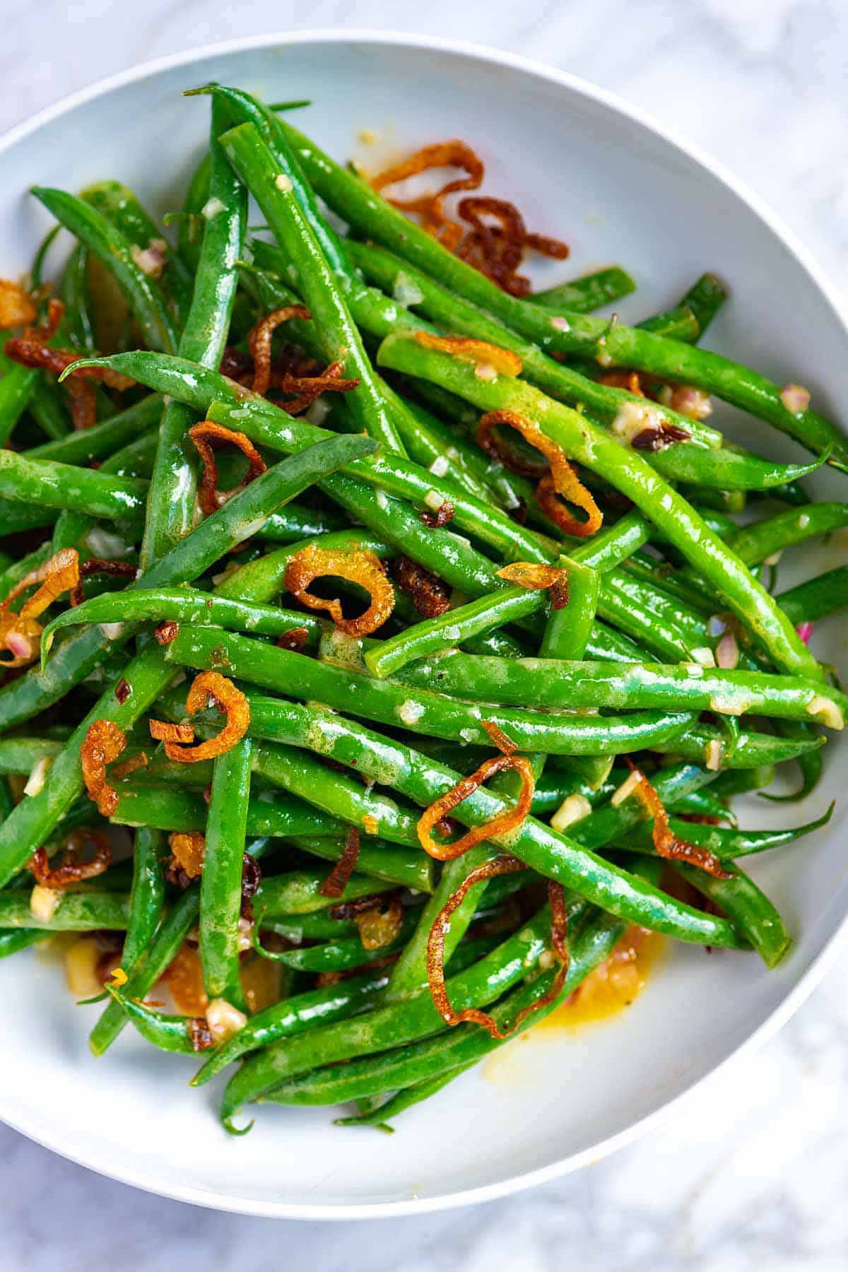 white bowl with green beans and crispy shallots.