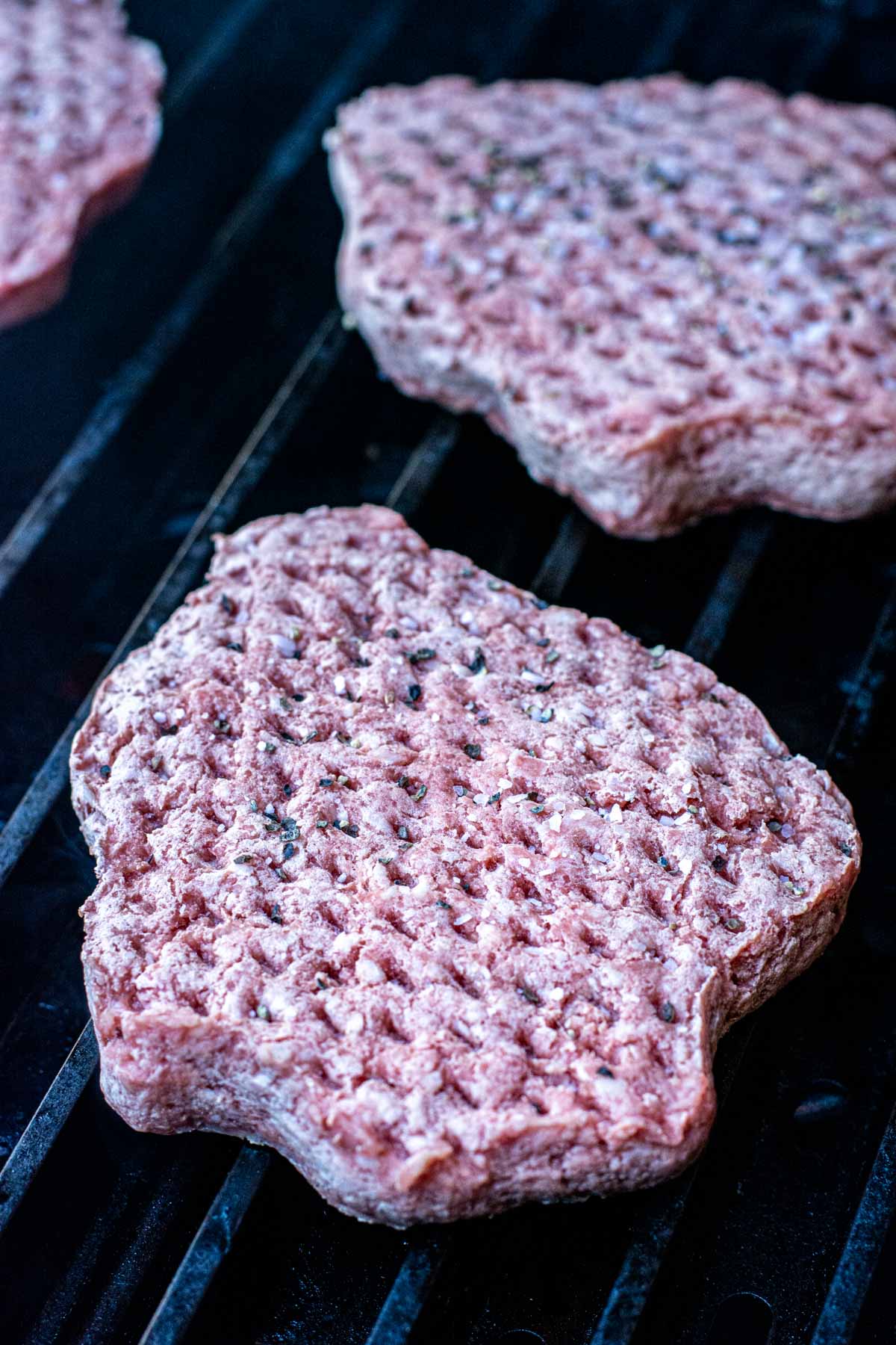 Raw frozen burger patties on the grill.