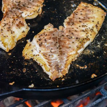 two fillets in a cast iron skillet over a hot grill.