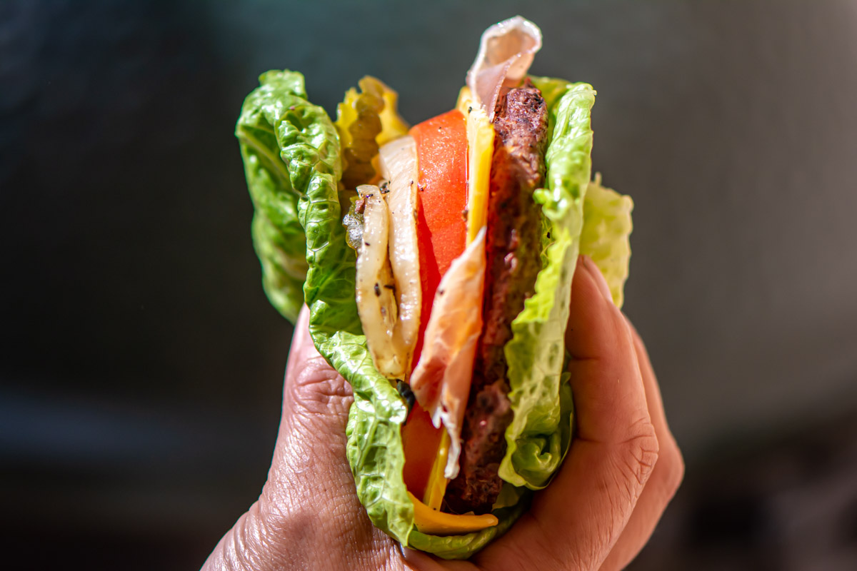 holding a burger with lettuce as the bun.