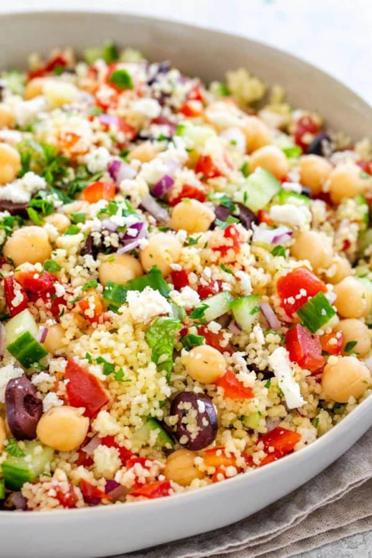 bowl of colorful couscous salad filled with olives, peppers, tomatoes and chickpeas for a mediterranean tast.