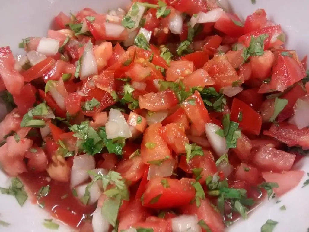 white bowl with a smoked summer salsa loaded with tomatoes, onions, and cilantro.