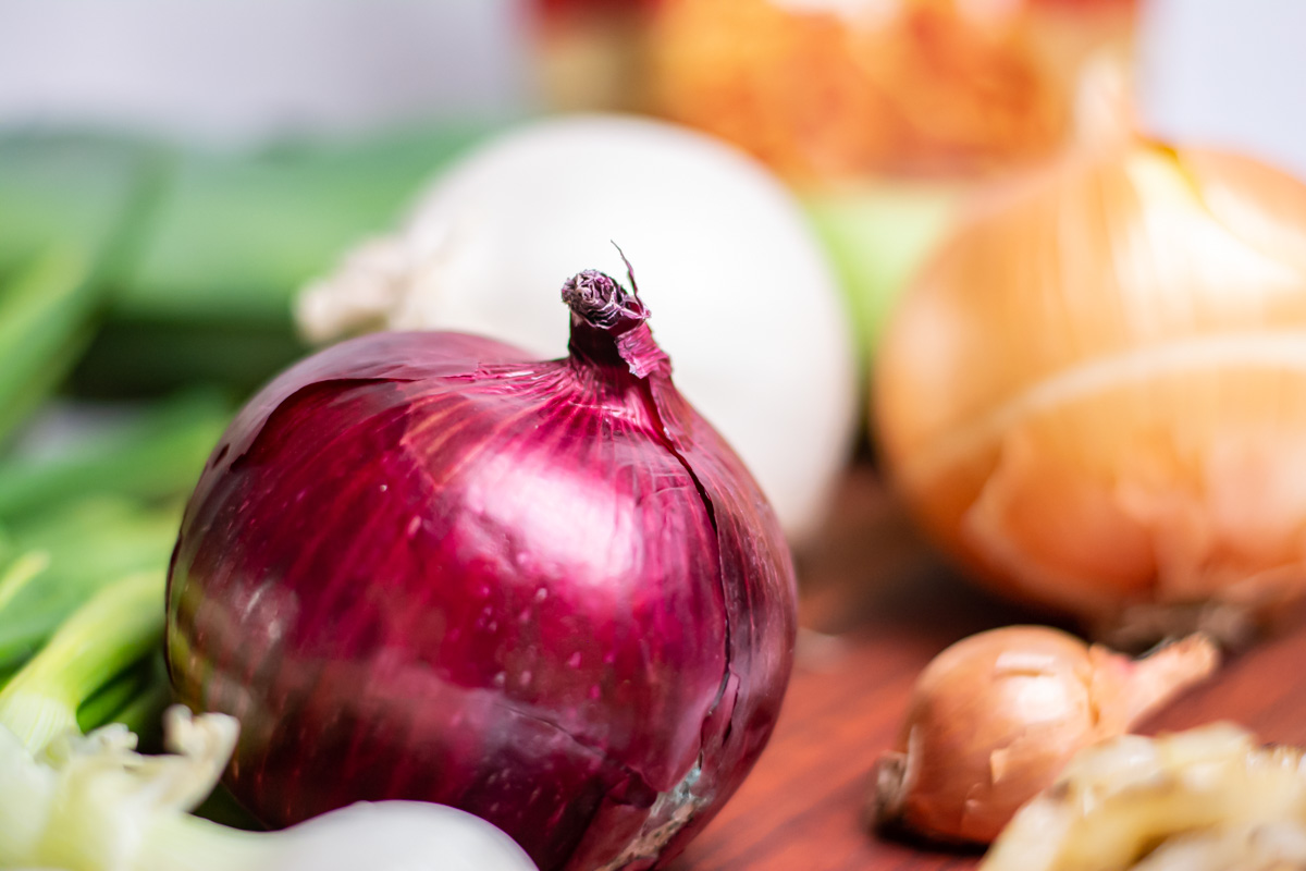 closeup of a red onion with other varieties in the background.