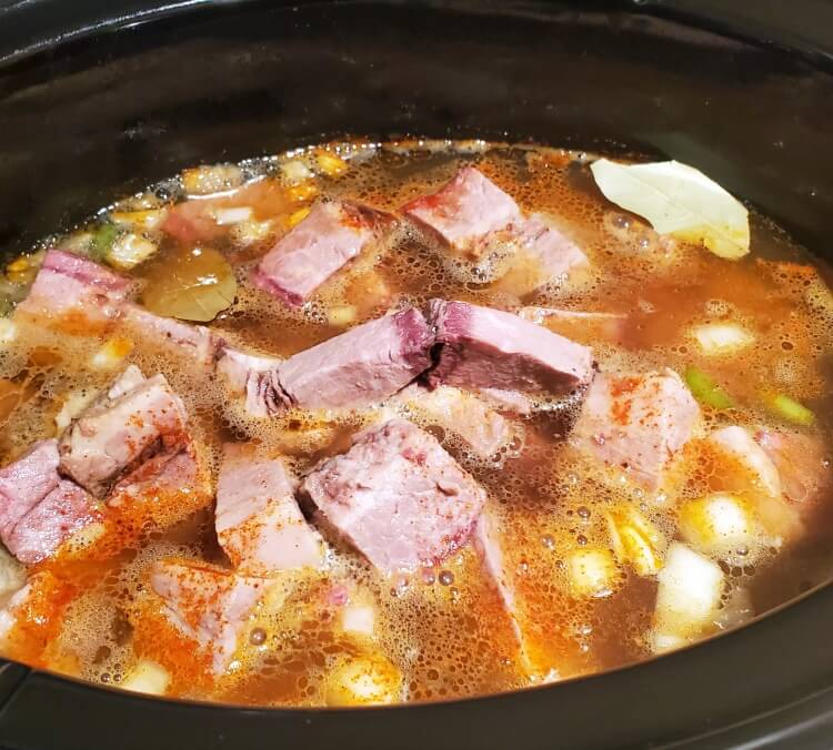 inside the crock pot filled with veggies and chunks of smoked brisket.
