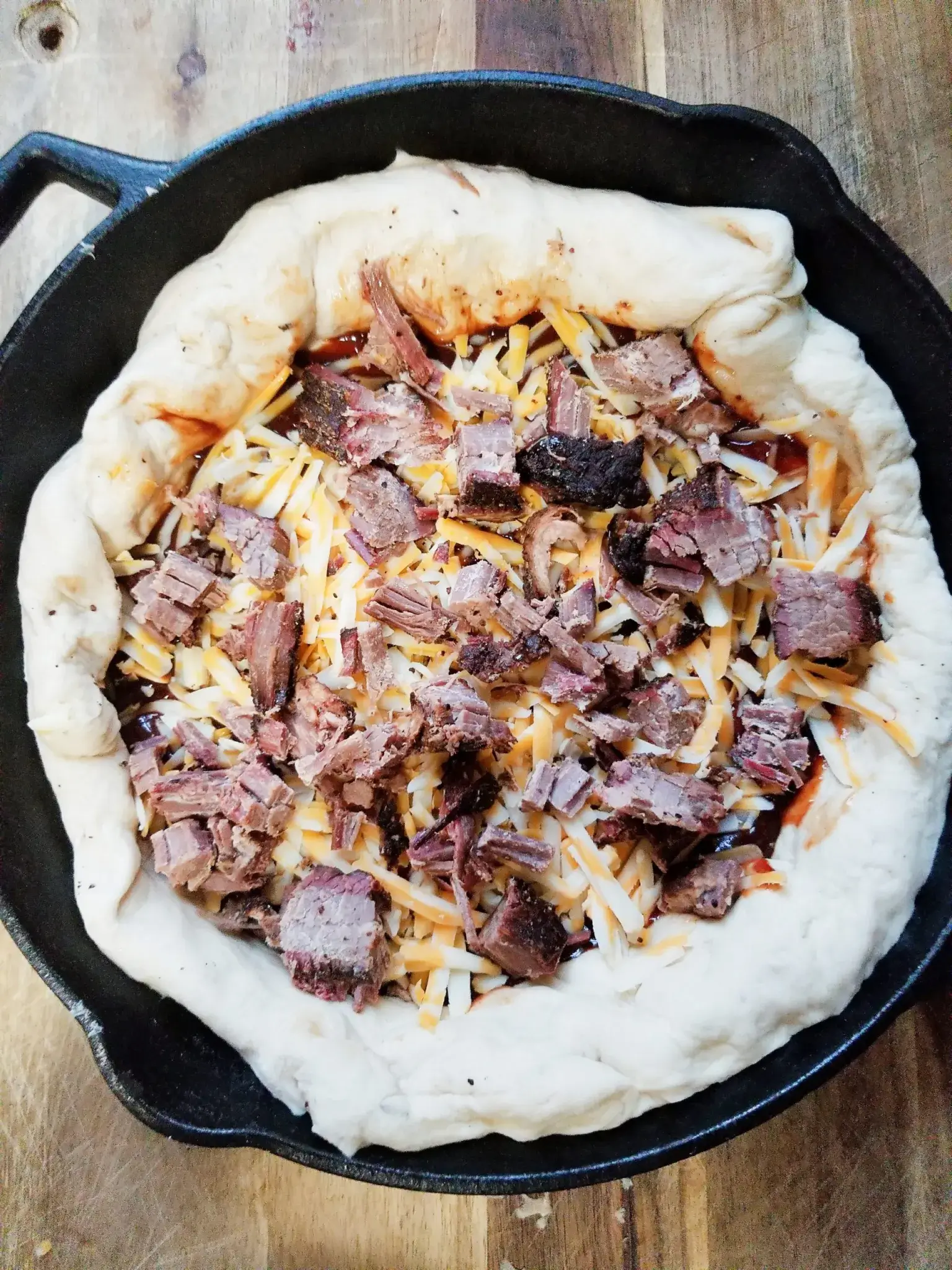brisket, cheese and pizza dough on a cast iron skillet.
