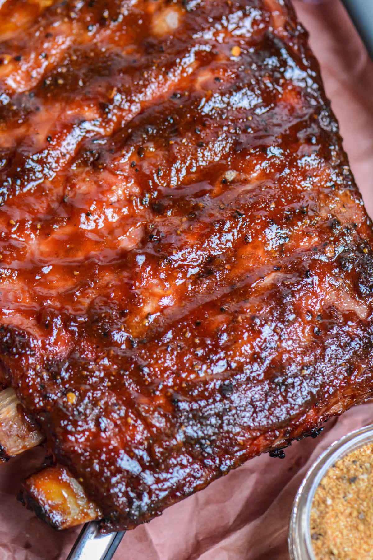 top down view of rack of ribs on pink butcher paper with a jar of the dry rub in the corner.