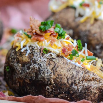 fully loaded salt crusted smoked baked potato topped with chives, cheese, bacon and sour cream.