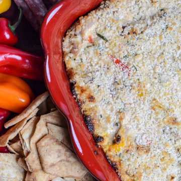 top down view of red baking dish, crackers and peppers and the smoked tuna dip right out of the oven.