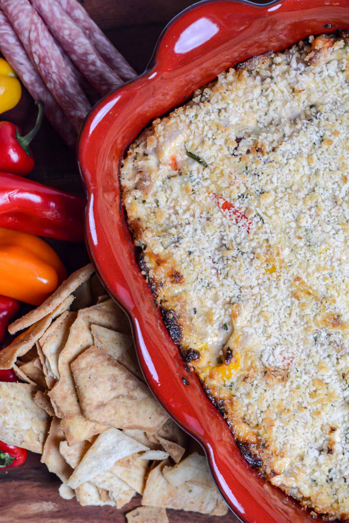 top down view of red baking dish, crackers and peppers and the smoked tuna dip right out of the oven.