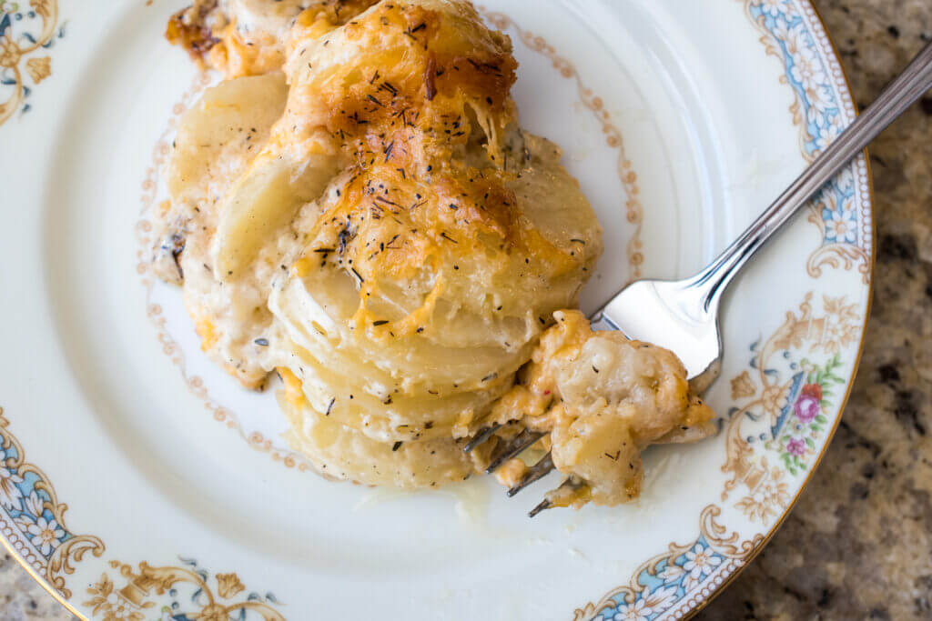top down view of a plate of scalloped potatoes with a fork.
