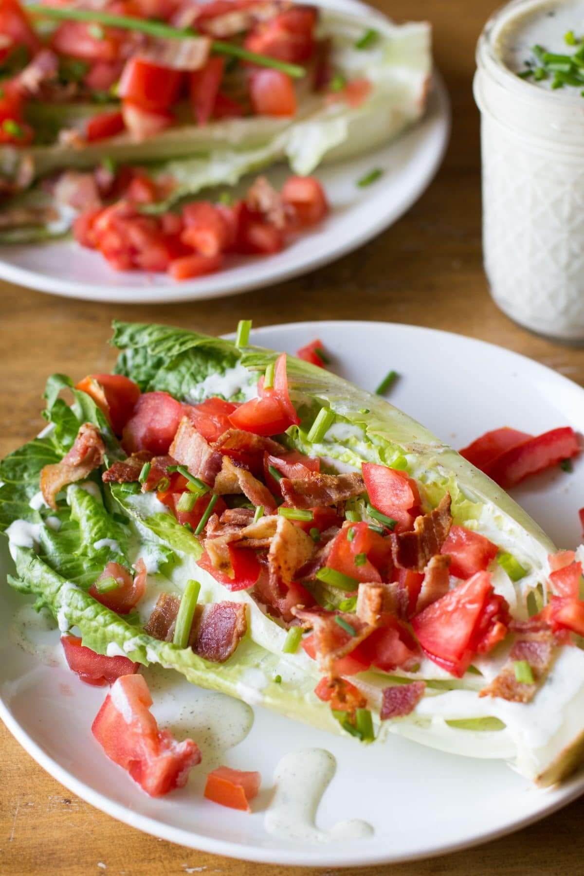 wedge of romaine lettuce with tomatoes, green onions and bacon.